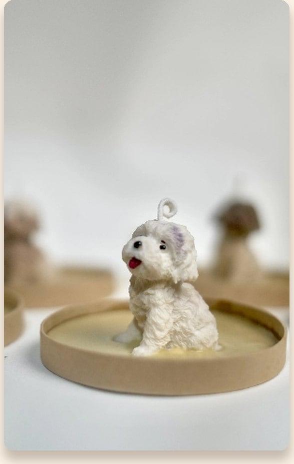 Hand-sculpted mini white puppy candle sitting on a kraft coaster