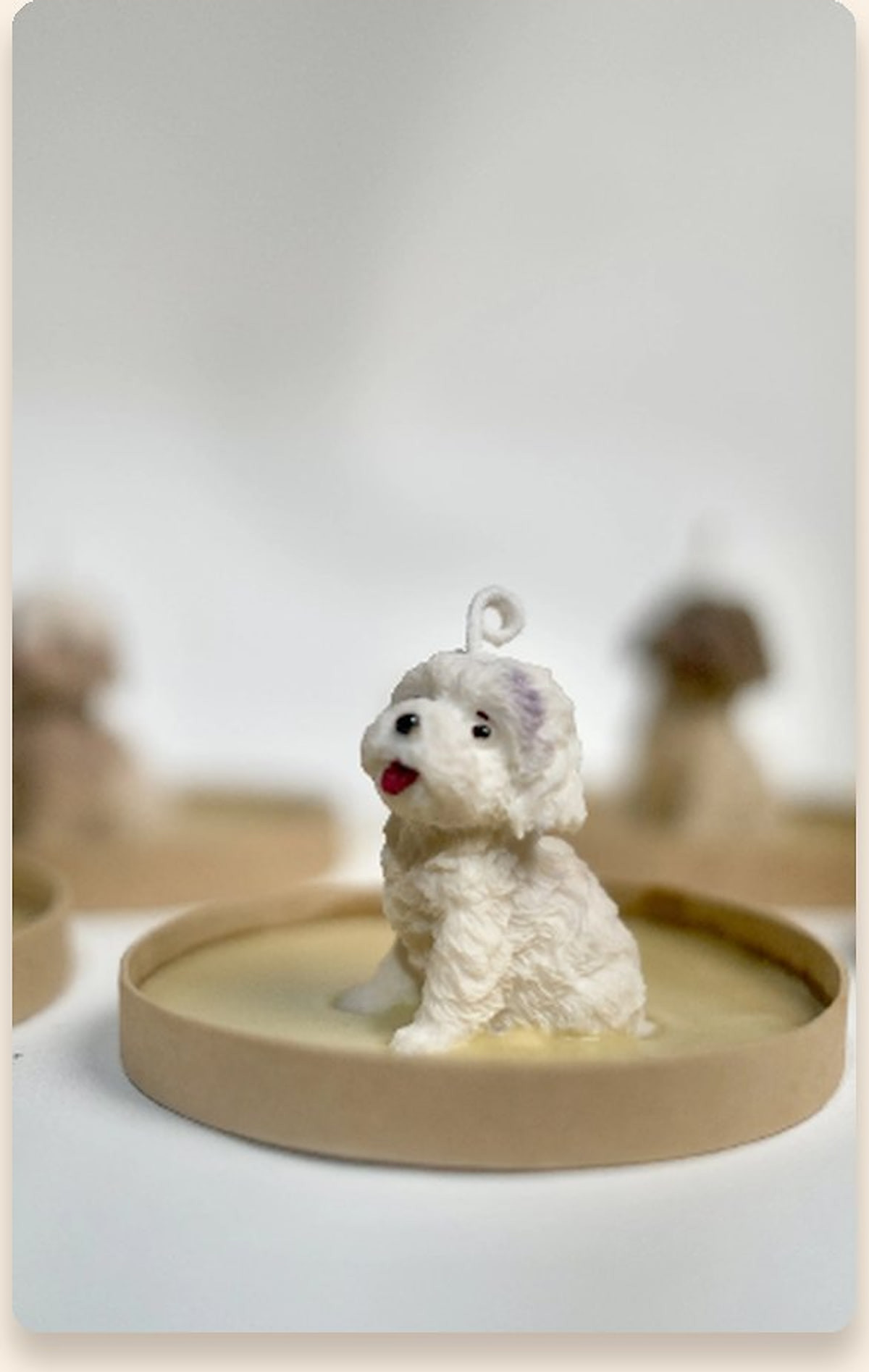 Hand-sculpted mini white puppy candle sitting on a kraft coaster