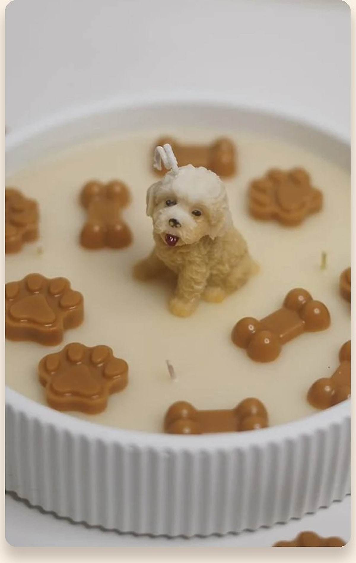 Round candle with a sculpted miniature dog surrounded by wax paw and bone charms